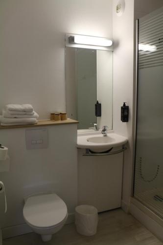 a bathroom with a toilet and a sink and a mirror at Ibis Budget Agen in Le Passage