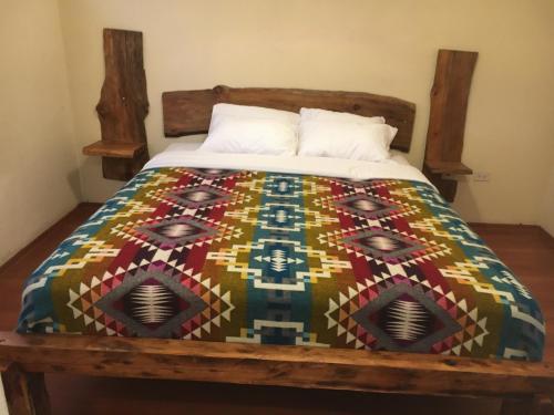 a bed with a colorful quilt on it at CASA IDEAL in Riobamba
