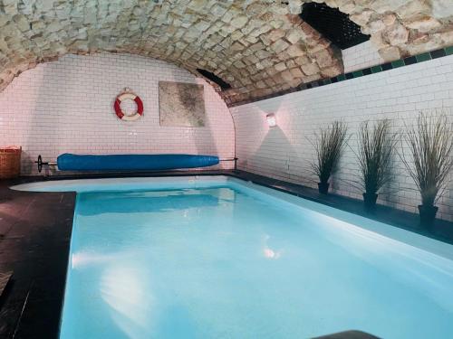 uma grande piscina num quarto de tijolos com piscina em Maison piscine centre historique de Romainville em Romainville