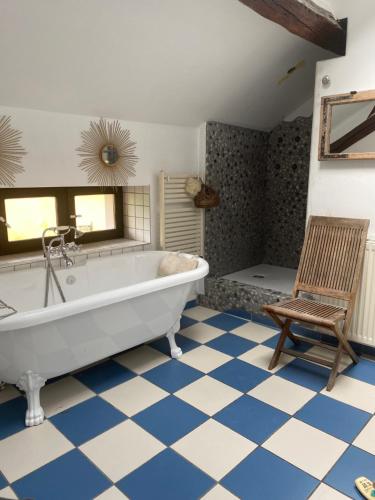 uma ampla casa de banho com uma banheira e uma cadeira. em Maison piscine centre historique de Romainville em Romainville