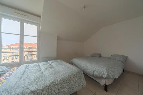 a bedroom with two beds and a large window at PARIS/DISNEY 50m2 +Balcon Paris’land Appartement in Bussy-Saint-Georges
