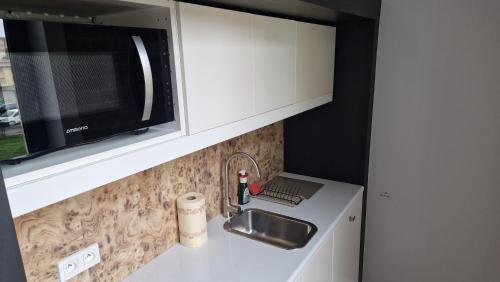 eine Küchentheke mit einer Spüle und einer Mikrowelle in der Unterkunft Przytulna Kawalerka w Kamienicy in Olsztyn