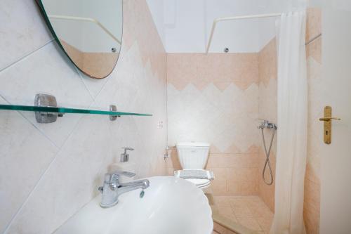 a bathroom with a sink and a toilet and a mirror at Villa Marilia in Astérion