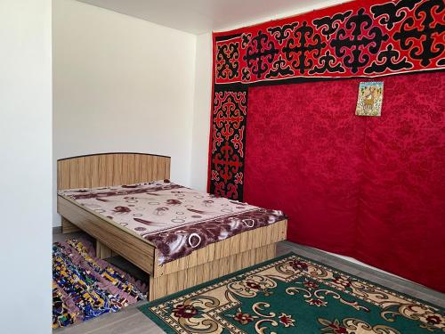 a room with two beds and a red wall at Handicraft house in Karakol