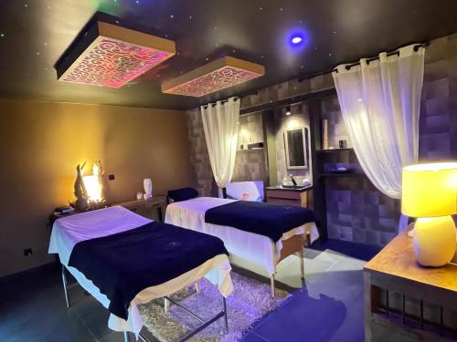 two beds in a room with lights on the ceiling at La Terrasse Des Spas in Hazebrouck