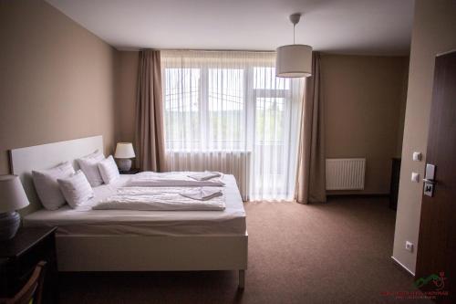 a bedroom with a bed and a large window at Selfness Hotel Vadvirág Mátraszentimre in Mátraszentimre