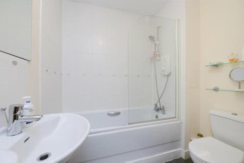 baño blanco con ducha y lavamanos en Ferry Gait en Edimburgo