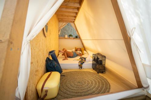 a person laying on a bed in a tent at Kampaoh Hostel El Palmar in El Palmar