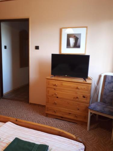 a bedroom with a television on a dresser with a chair at Magdaléna Vendégház in Esztergom