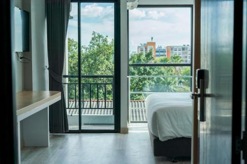 a bedroom with a bed and a view of a balcony at Goodday Hotel in Ban Nong Waeng