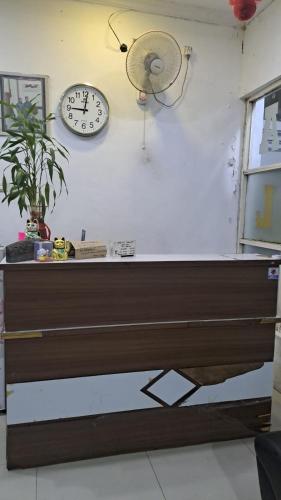 een bureau met een klok en een ventilator aan de muur bij King Plaza Homestay in Tanjungredep