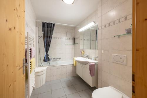a bathroom with a toilet and a sink and a tub at Trü-Sura Nr. 7 in Scuol