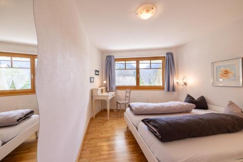 two beds in a room with a desk and windows at Trü-Sura Nr. 7 in Scuol