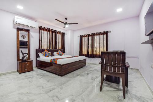 a bedroom with a bed and a chair at FabHotel Vishwa Palace in Ahmedabad