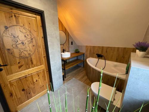 a bathroom with a wooden door and a sink at Widokówka - dom na wyłączność z pięknym widokiem i balią in Szczyrk