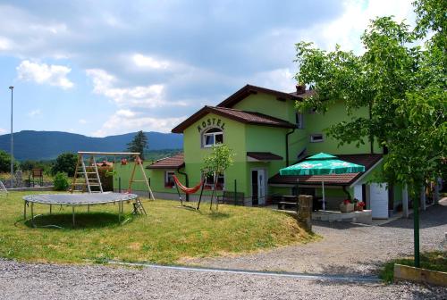 a playground in front of a green house with a slide at Hostel Ociski Raj in Kozina