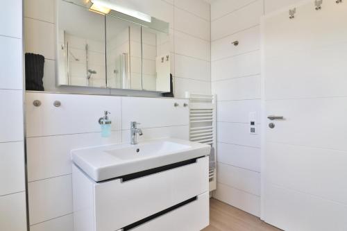 een witte badkamer met een wastafel en een spiegel bij Düünleev in Langeoog