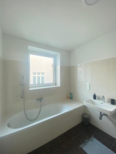 uma casa de banho branca com uma banheira e um lavatório em Home Sweet Home Vienna - Penthouse em Viena