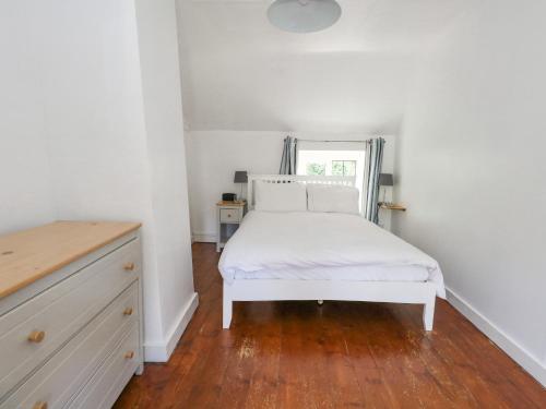 a bedroom with a white bed and a window at Wayside in Beaminster