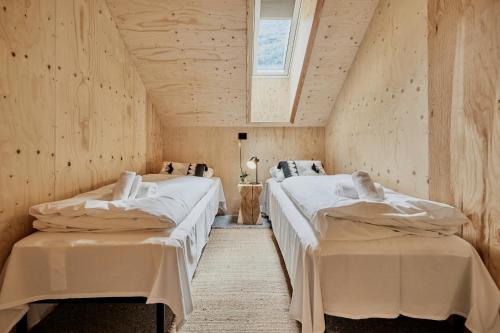 two beds in a room with wooden walls at Lodgen Stryn in Stryn