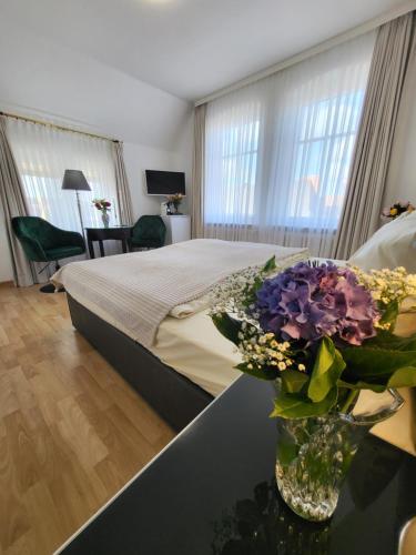 Villa Wally في فيسترلاند: غرفة نوم مع سرير و مزهرية من الزهور على طاولة