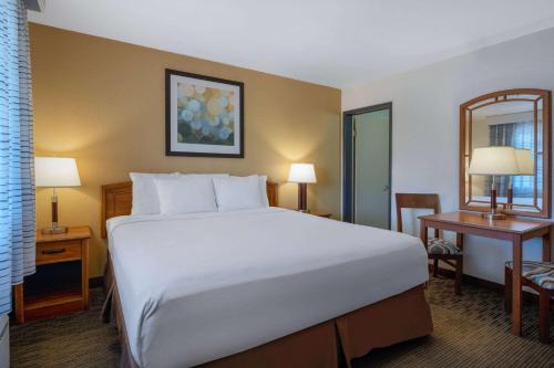 a hotel room with a large bed and two tables at Days Inn by Wyndham Encinitas Moonlight Beach in Encinitas