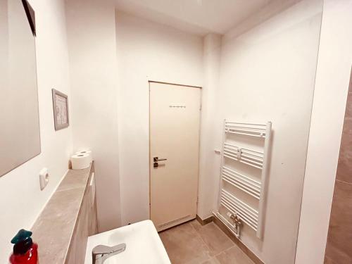 Baño blanco con aseo y puerta en Cozy Apartment close to Hamburg, en Reinbek