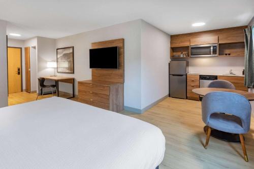 a hotel room with a bed and a desk and a kitchen at Super 8 by Wyndham Cornwall ON in Cornwall