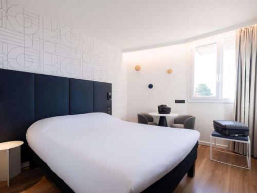 um quarto com uma grande cama branca e uma janela em ibis Beziers Est Mediterranee A9/A75 em Béziers