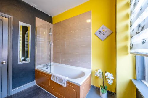 a bathroom with a white tub and yellow walls at *1ES* For your most relaxed & Cosy stay + Free Parking + Free Fast WiFi * in Leeds