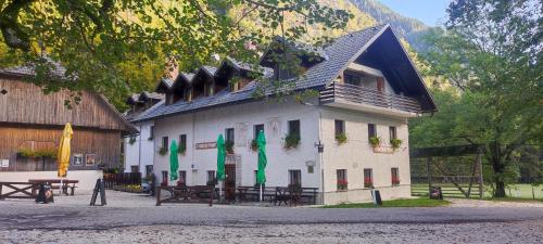 een groot wit gebouw met tafels en groene vlaggen bij Turisticna Kmetija Psnak in Mojstrana