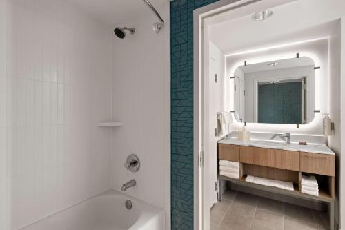 een badkamer met een bad, een wastafel en een spiegel bij Homewood Suites by Hilton West Palm Beach in West Palm Beach