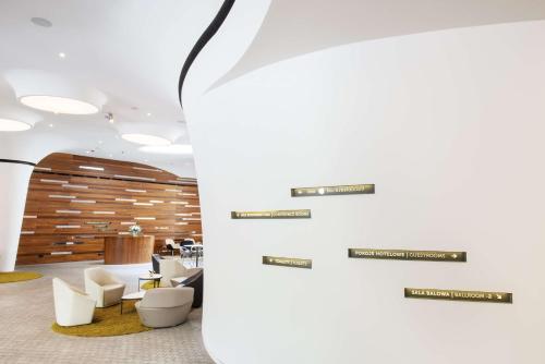 a lobby with white chairs and a wall with signs at DoubleTree by Hilton Wroclaw in Wrocław