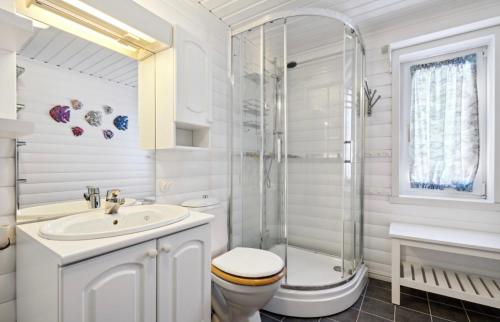 a white bathroom with a shower and a toilet and sink at Brensholmen Beach House in Tromsø