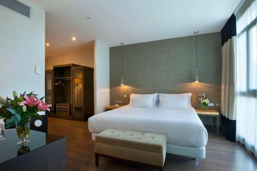 a bedroom with a large white bed and a chair at NH Collection Sevilla in Seville