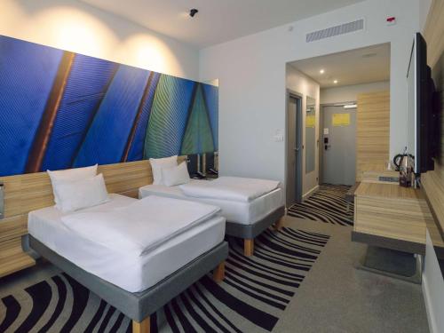a bedroom with two beds and a painting on the wall at Novotel Arkhangelsk in Arkhangelsk
