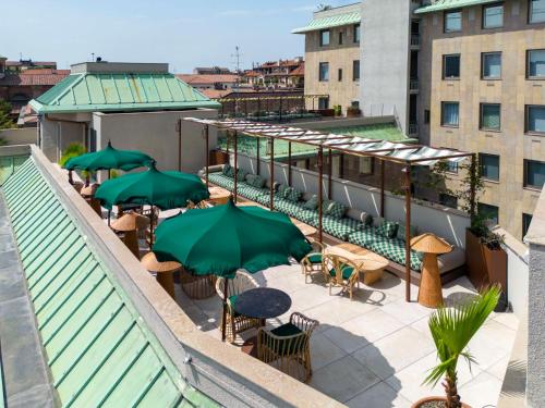 an outdoor patio with tables and umbrellas on a roof at Radisson Collection Hotel, Santa Sofia Milan in Milan
