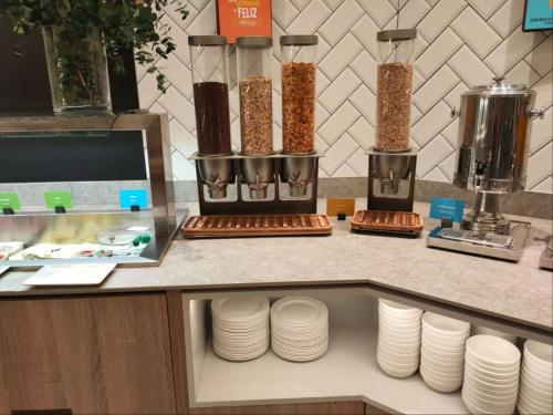 a counter with stacks of white plates on a counter at Hampton By Hilton Alcobendas Madrid in Alcobendas