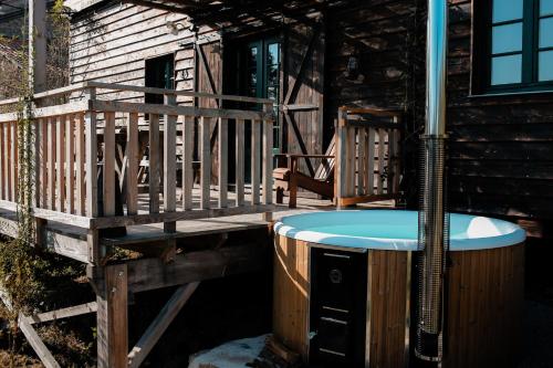 bañera de hidromasaje en la cubierta de una cabaña en La ferme du pont de Maumy, cabane au bord de l'étang et bain nordique, en Busserolles