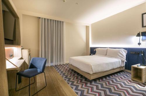 Pokój hotelowy z łóżkiem i krzesłem w obiekcie Hampton By Hilton Alcobendas Madrid w mieście Alcobendas
