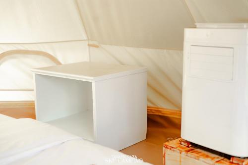 a room with two white tables next to a bed at Tawaen Caza Sky Camping in Ko Larn