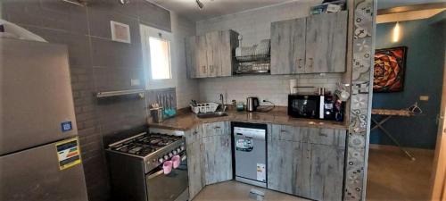 a kitchen with wooden cabinets and a stove at Palermo Chalet in Marina Wadi Degla Ain Sokhna with 250 Sqm Private Garden & near to the Beach in Ain Sokhna