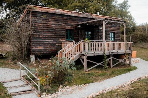 eine alte Blockhütte mit einer Holzterrasse und einer Treppe in der Unterkunft La ferme du pont de Maumy, cabane au bord de l'étang et bain nordique in Busserolles