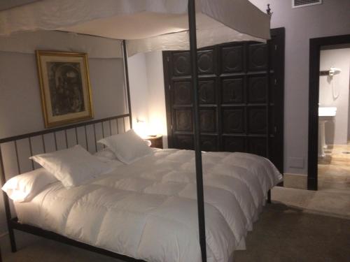 a bedroom with a large white bed with a canopy at Hotel Palacio de Mengibar in Mengibar
