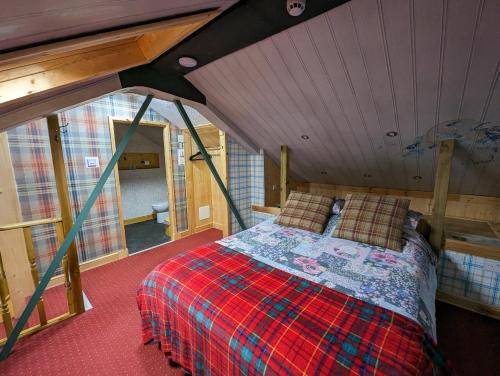 um quarto com uma cama no sótão de uma casa em The Steading Highland Glen Lodge em Drumnadrochit