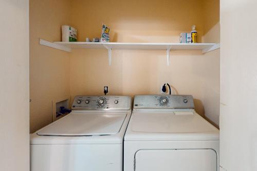 two washing machines in a laundry room with shelves at Killeen Serene in Killeen