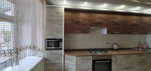 a kitchen with wooden cabinets and a stove top oven at Затишна квартира біля парку Відродження in Ternopilʼ