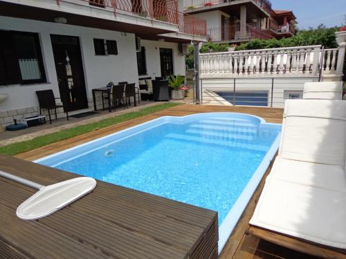a swimming pool with a table and chairs next to a house at Apartments Butinar Pri Kapitanu in Ankaran