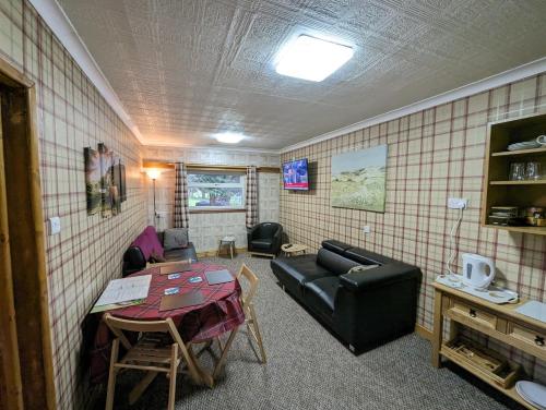 a living room with a couch and a table at The Steading Highland Glen Lodge in Drumnadrochit
