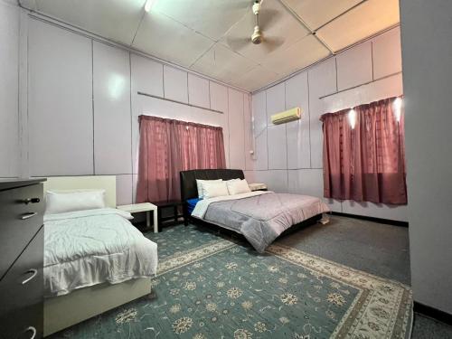 a bedroom with two beds and a dresser in it at Traditional 4-bedroom Kampung House in Kota Bharu in Kampong Kebun Tok Salim